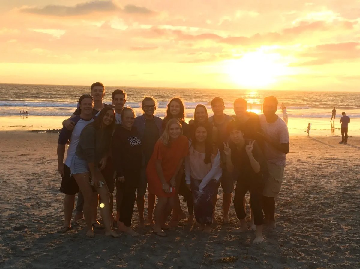 Gruppe junger Menschen posiert am Strand bei Sonnenuntergang.