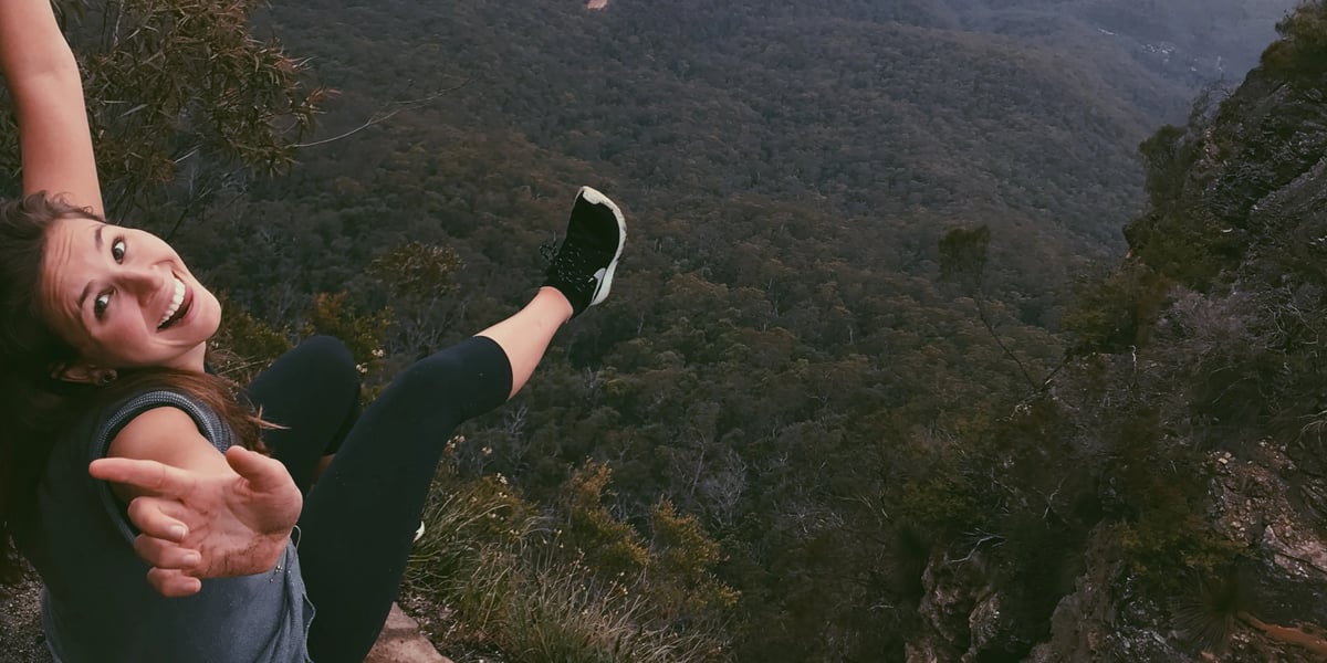 Eine Studentin der University of Newcastle posiert über Bergen und Wald Australiens