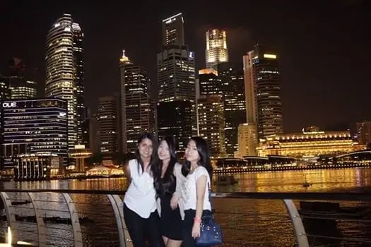 Drei Studentinnen der Curtin University Singapore am Hafen bei Nacht