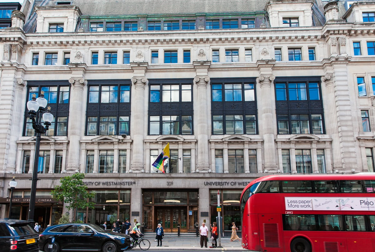 Historisches Gebäude der University of Westminster in London mit vorbeifahrendem roten Doppeldeckerbus.